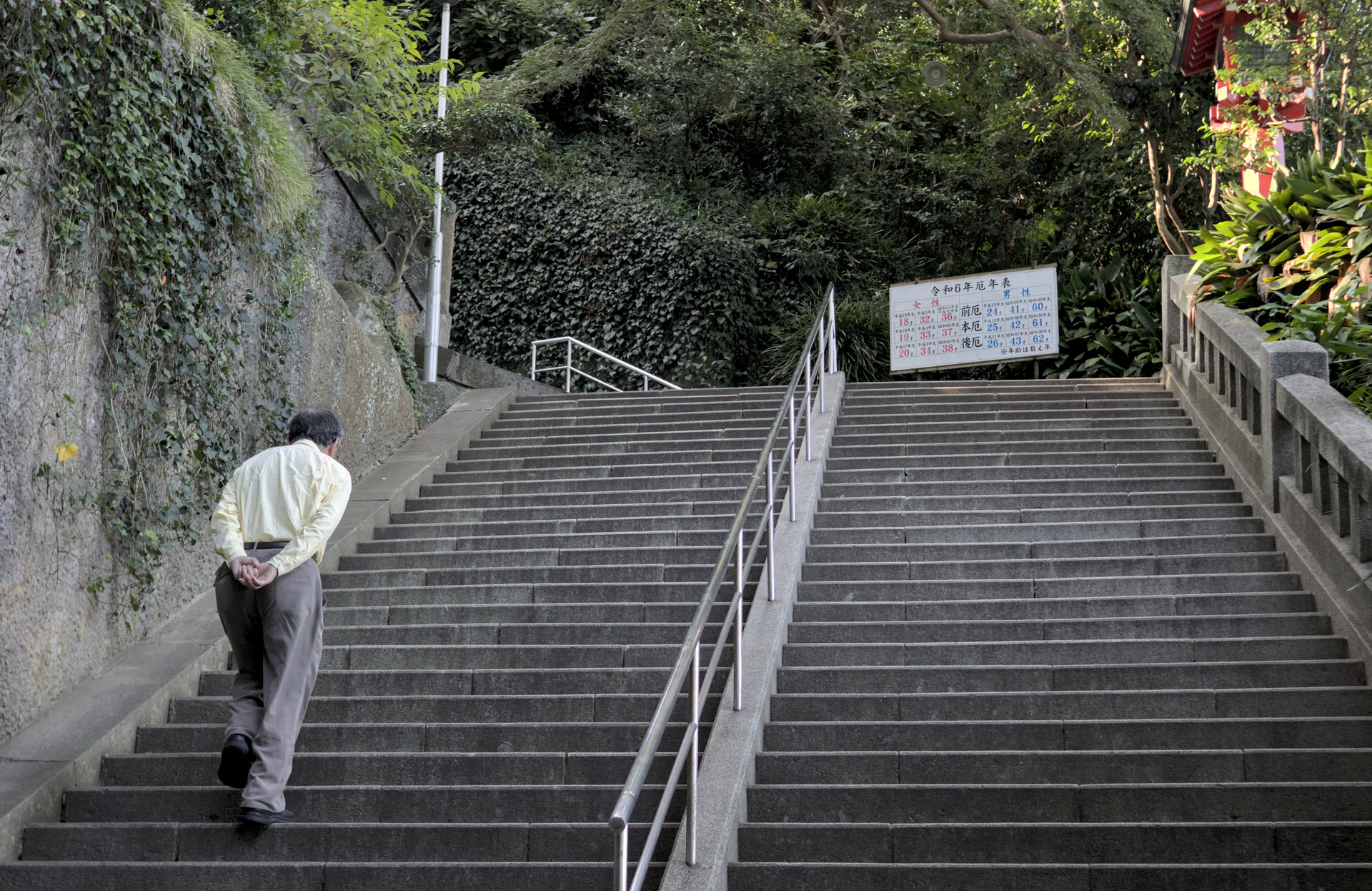 Old man in formal clothes walking up a staircase.